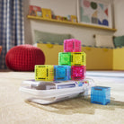 Colorful building blocks on a white surface with a child's room in the background
