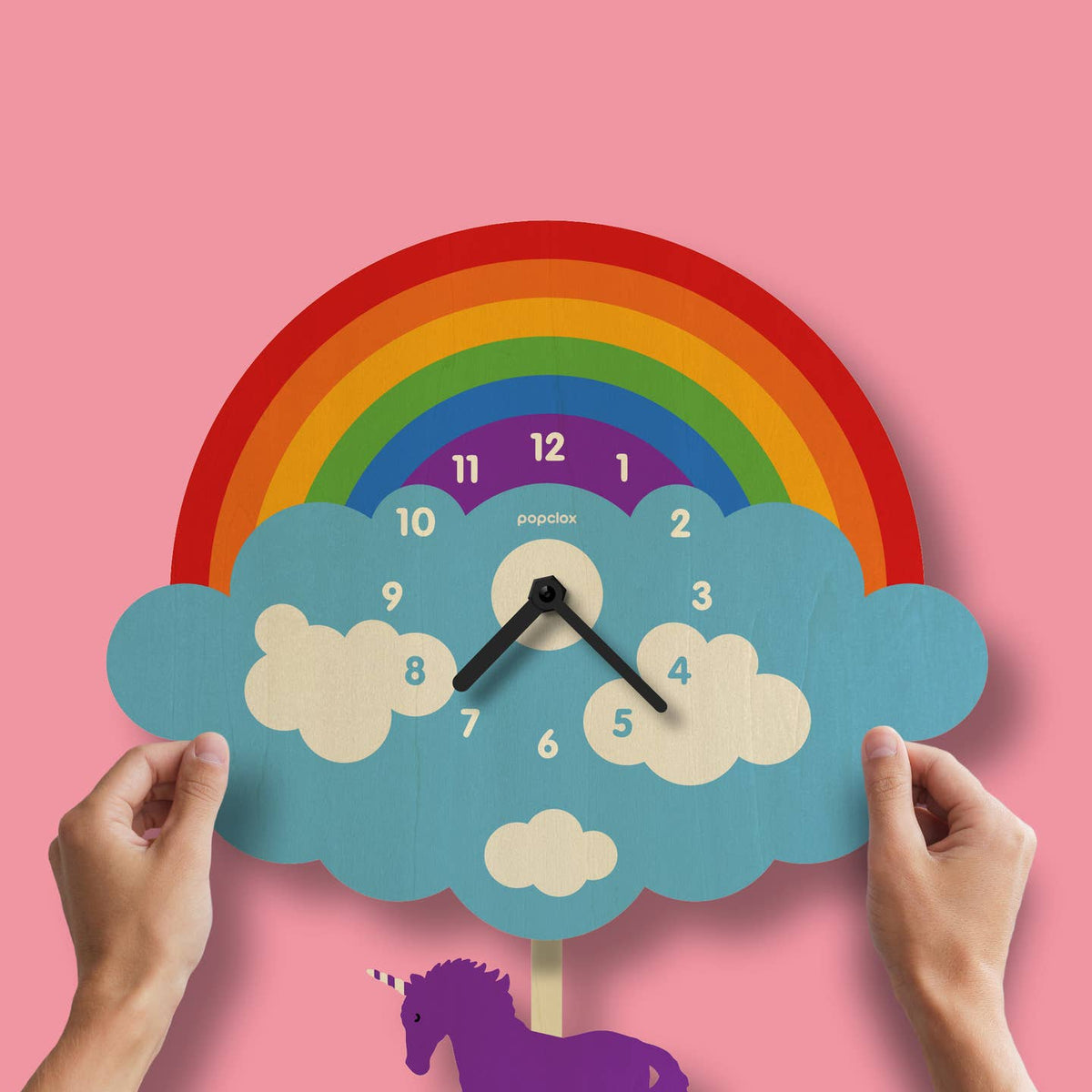 Children's clock with rainbow and cloud design on a pink background