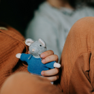 Person holding a small gray mouse toy with a blue sweater.