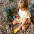 Child playing in sand with toys on a beach