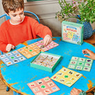 Child playing a board game with colorful cards on a blue table.