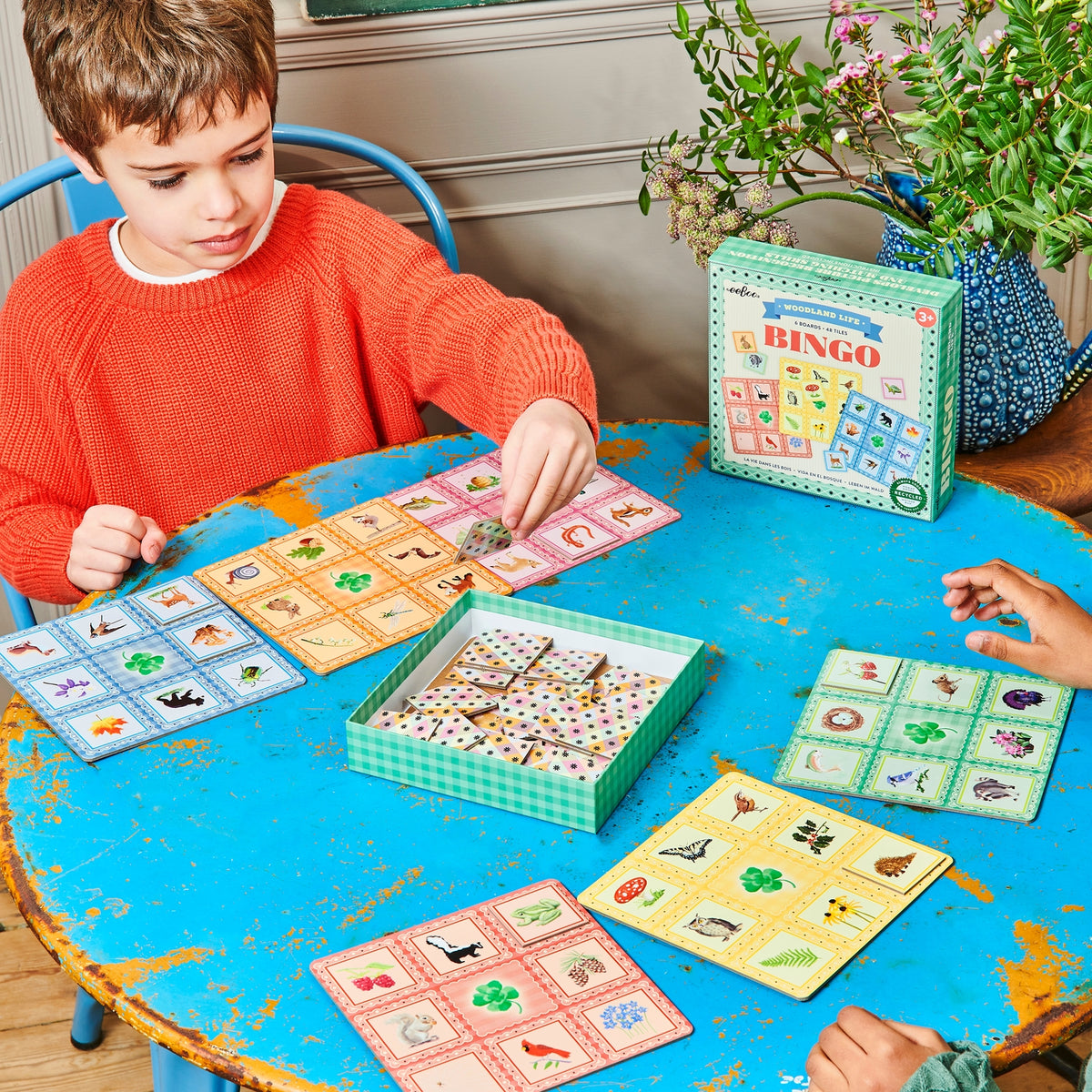 Child playing a board game with colorful cards on a blue table.