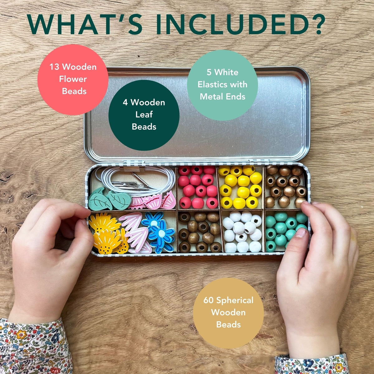 Open tin with wooden beads and accessories on a wooden surface, showing what's included.