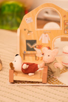 Small plush dog and pig in front of a wooden house with a mirror.