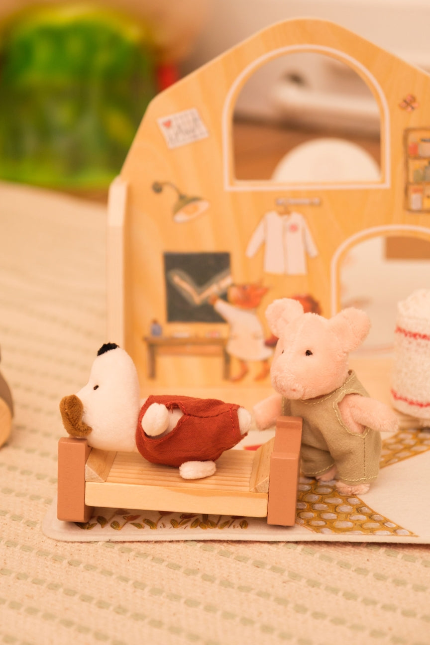 Small plush dog and pig in front of a wooden house with a mirror.