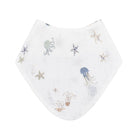 A white muslin baby bib featuring a delicate underwater print of jellyfish, starfish, and sea plants in muted blue, beige, and gray tones, shown flat against a solid white background.