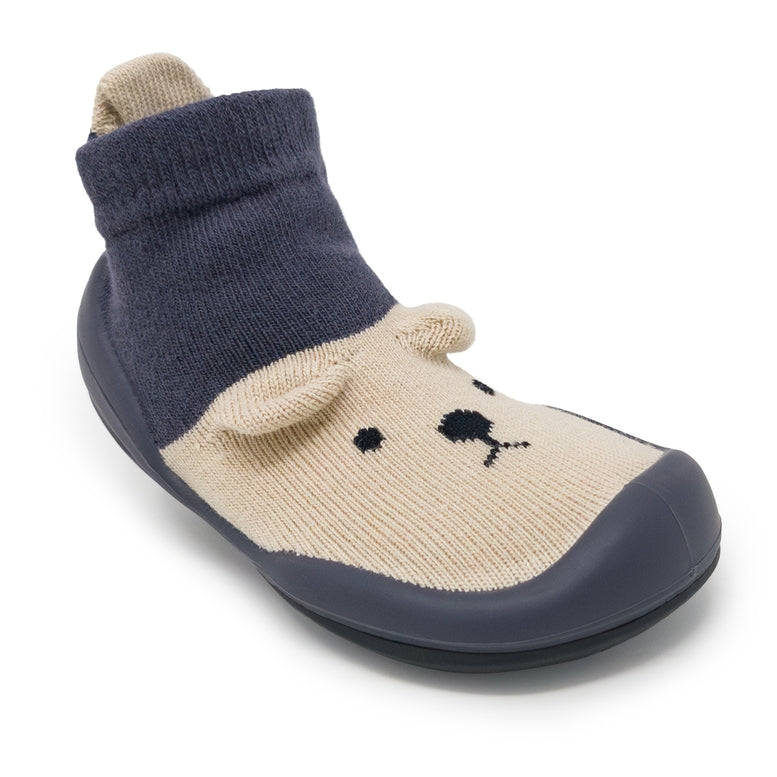 Children's slipper with navy blue top and beige bottom on a white background