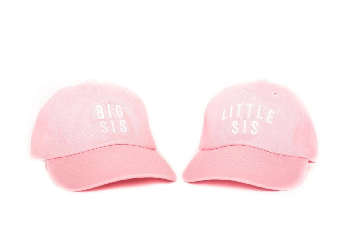 Two pink caps labeled 'BIG SIS' and 'LITTLE SIS' on a white background
