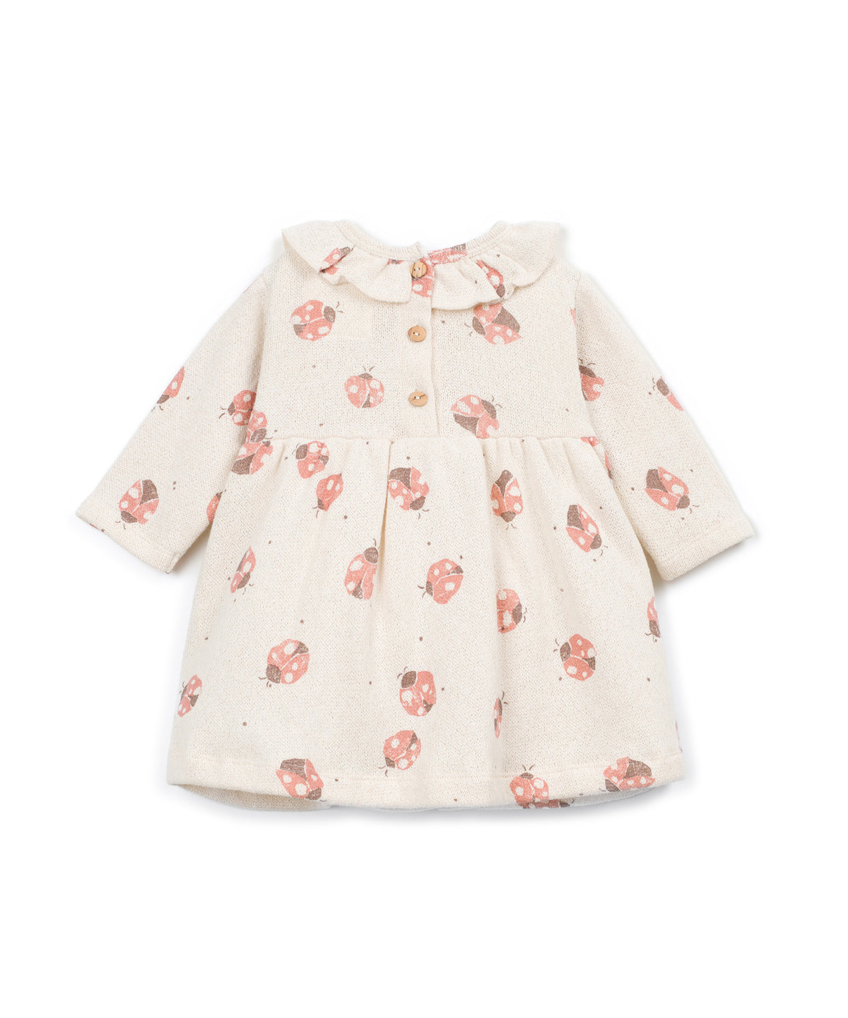 A long-sleeve baby dress in cream with a pink ladybug print, featuring a ruffled collar and button details at the chest.
