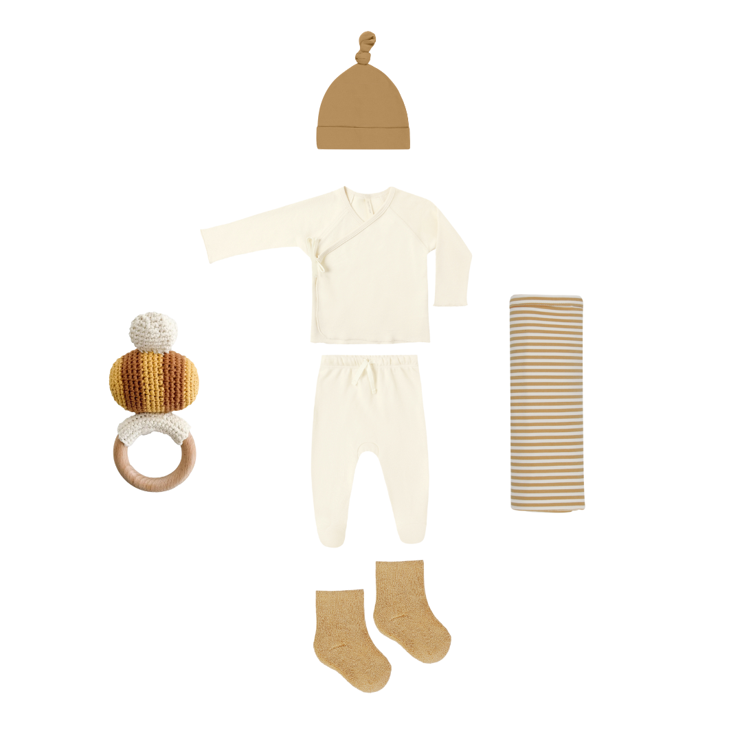 Baby clothing and accessories set including a onesie, hat, socks, and rattle on a white background