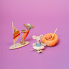 Toy mice with beach accessories on a purple background