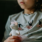 Child holding a small plush mouse toy with a dark background