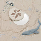 Beige quilt with embroidered sea-themed elements including a whale, jellyfish, sand dollar, and starfish.