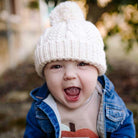 Child wearing a white knit hat and blue jacket outdoors