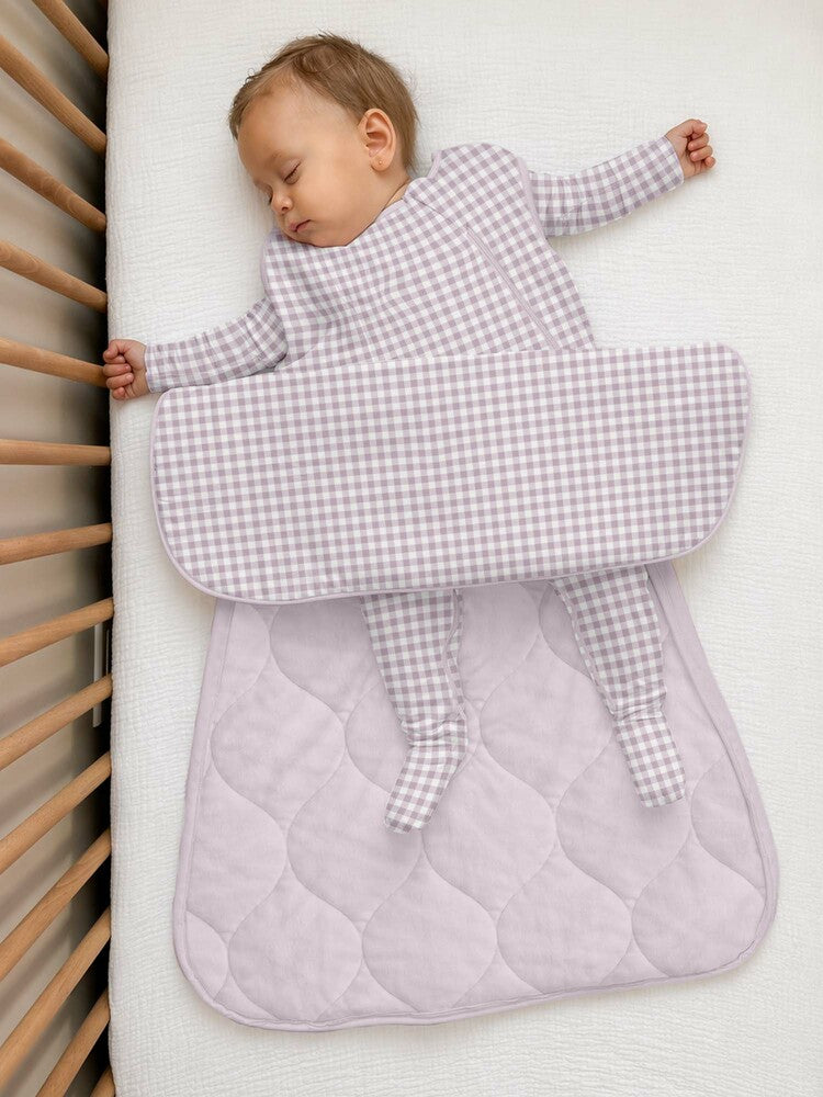 A baby sleeping in a pink gingham günamüna Sleep Sack.