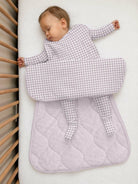 A baby sleeping in a pink gingham günamüna Sleep Sack.