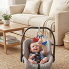 Baby in a car seat with a toy in a living room