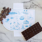 Chocolate bar, cocoa beans, and a diagram on a marble surface