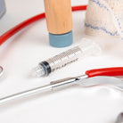 Plastipak syringe with a stethoscope and other medical tools on a white surface
