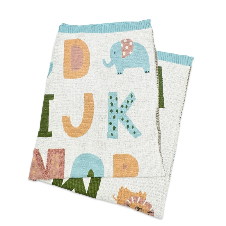 A folded knit baby blanket with a white background, featuring colorful alphabet letters and cartoon animal motifs including an elephant, lion, and hedgehog. The blanket has a light blue ribbed trim at the top and is shown on a clean white background.