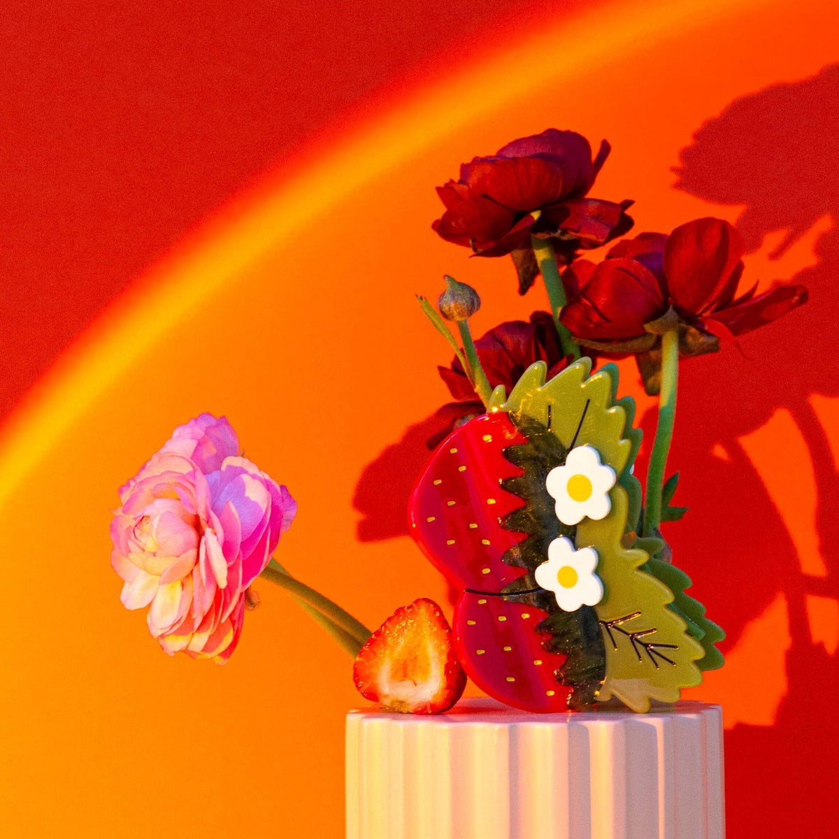 Decorative arrangement with flowers and a strawberry on a red background