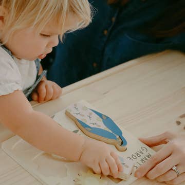 Child decorating a cookie with blue icing on a wooden table