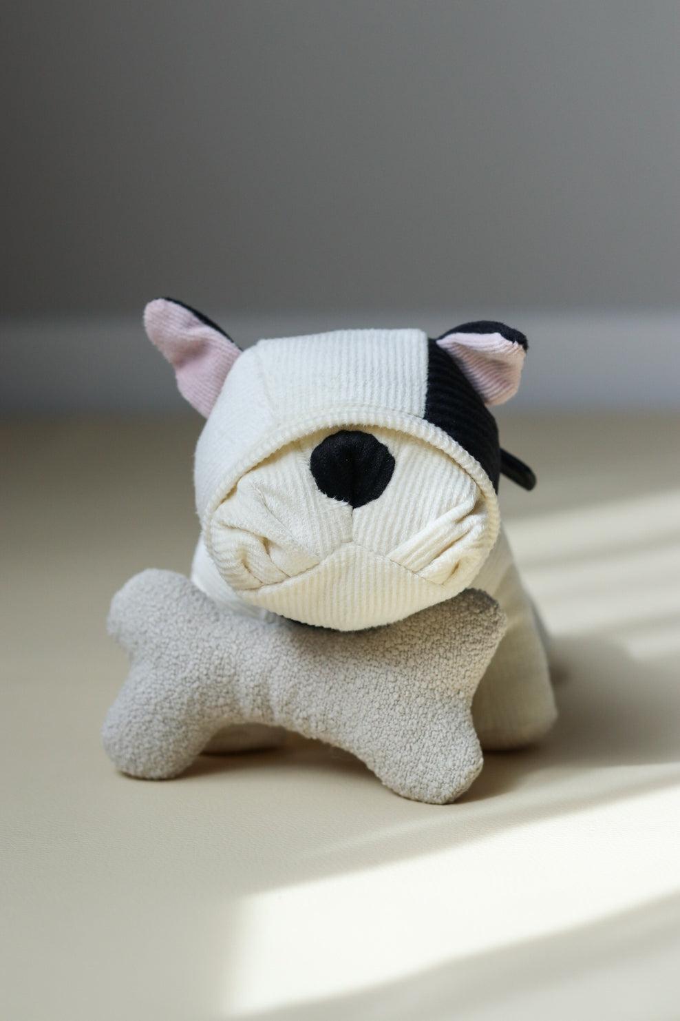 Stuffed animal toy resembling a cat with a sock over its head on a light surface.