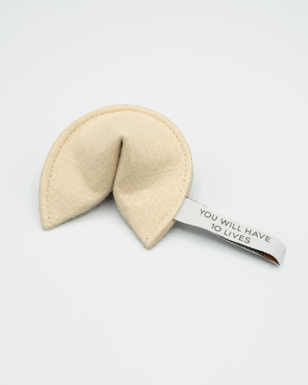 Beige fortune cookie-shaped toy with a tag on a white background
