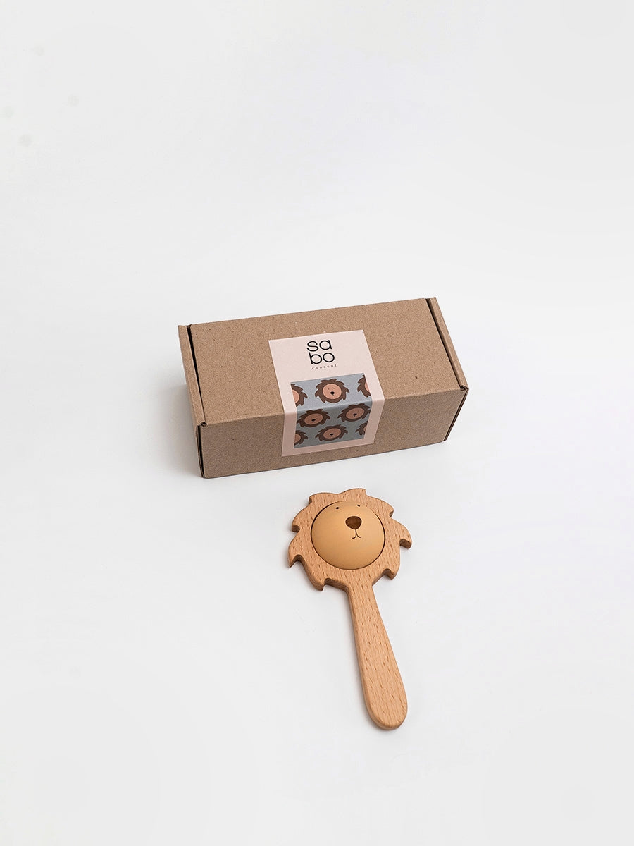 Wooden toy with a handle and bell next to a cardboard box on a white background
