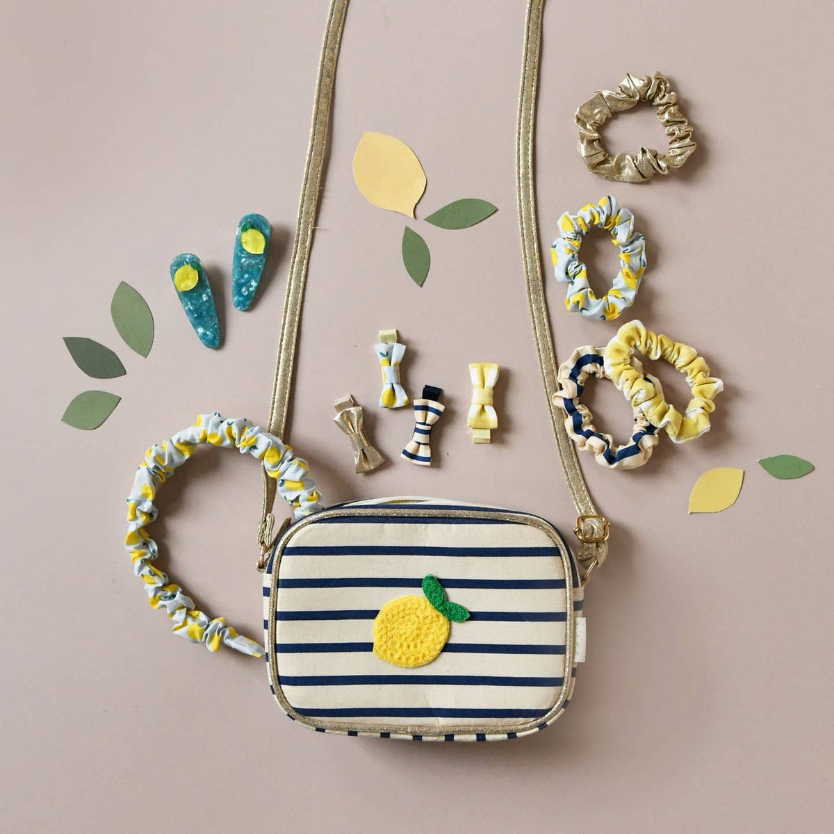 Striped bag with lemon design surrounded by accessories on a beige background