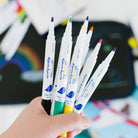 Hand holding a set of colorful markers with a blurred background