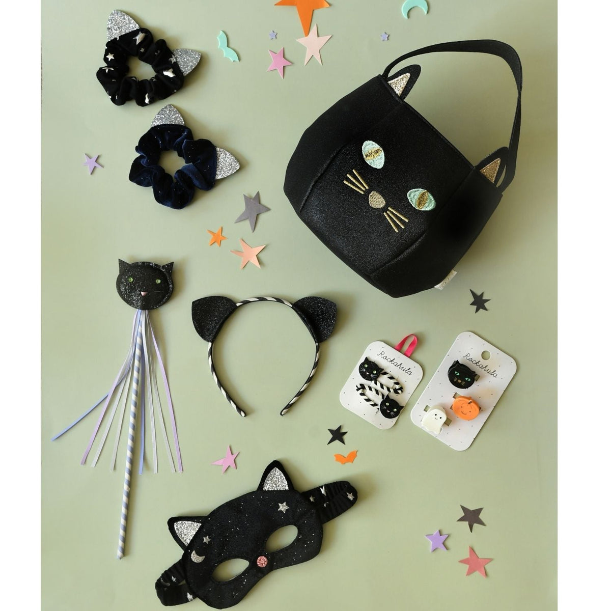 Collection of black cat-themed accessories on a light green background with star-shaped confetti.
