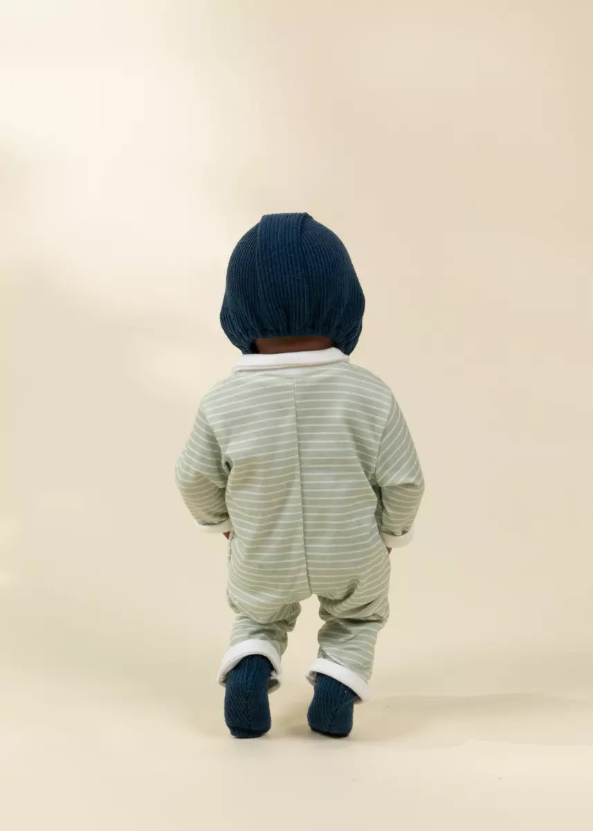 Baby in a striped onesie and navy hat on a beige background