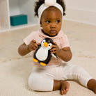 Child holding a penguin toy on a carpeted floor