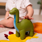 Child playing with a green dinosaur toy on a colorful mat