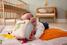 Baby lying on a bed holding a plush toy in a nursery setting