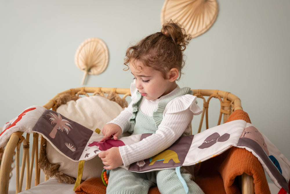 Child sitting in a crib reading a book with a colorful background