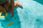Child playing with a toy in a pool labeled 'Quut'.