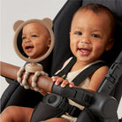 Baby sitting in a stroller with a mirror showing a reflection of the baby's face.