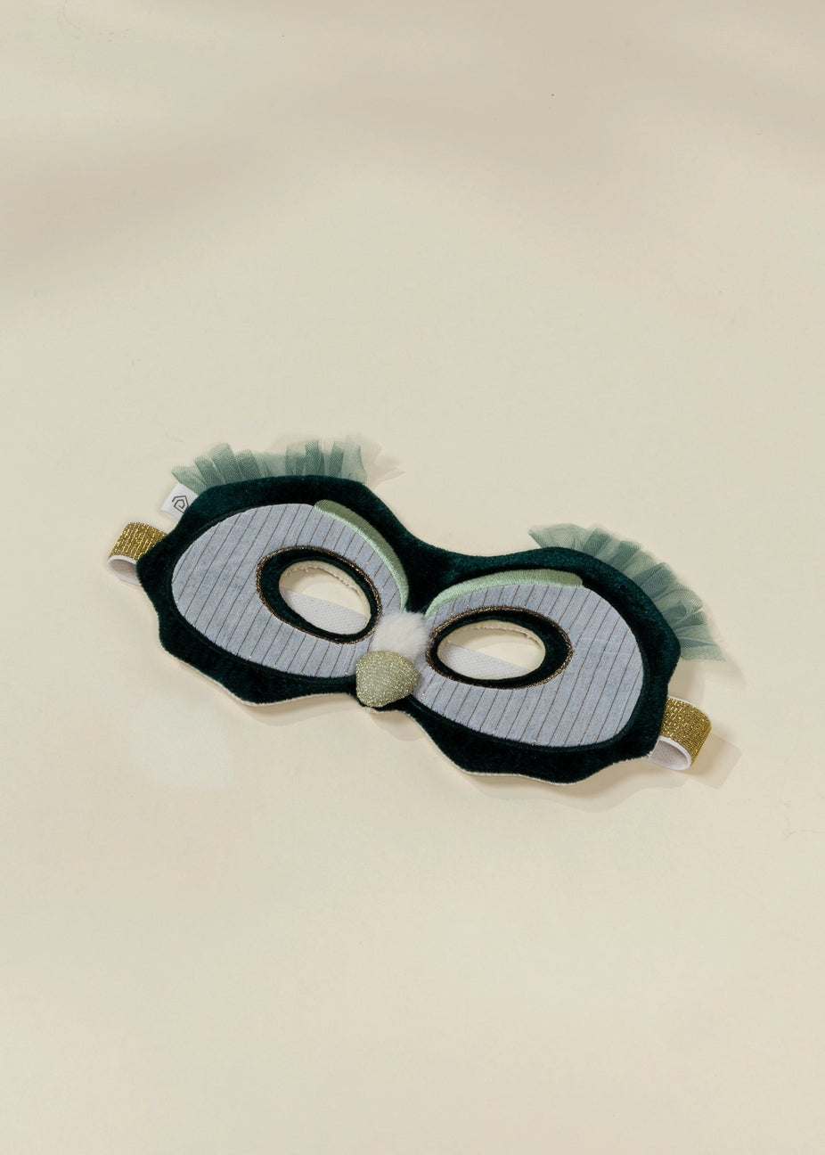 Eye mask with black frame and green fringes on a beige background