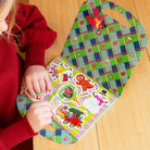 Child playing with a colorful Christmas-themed activity board on a wooden floor.