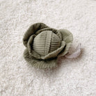 Green fabric flower on a textured white background