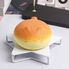 Round bread-shaped lamp with a face design on a white stand.