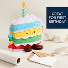Colorful plush toy resembling a birthday cake with a candle on a light background.