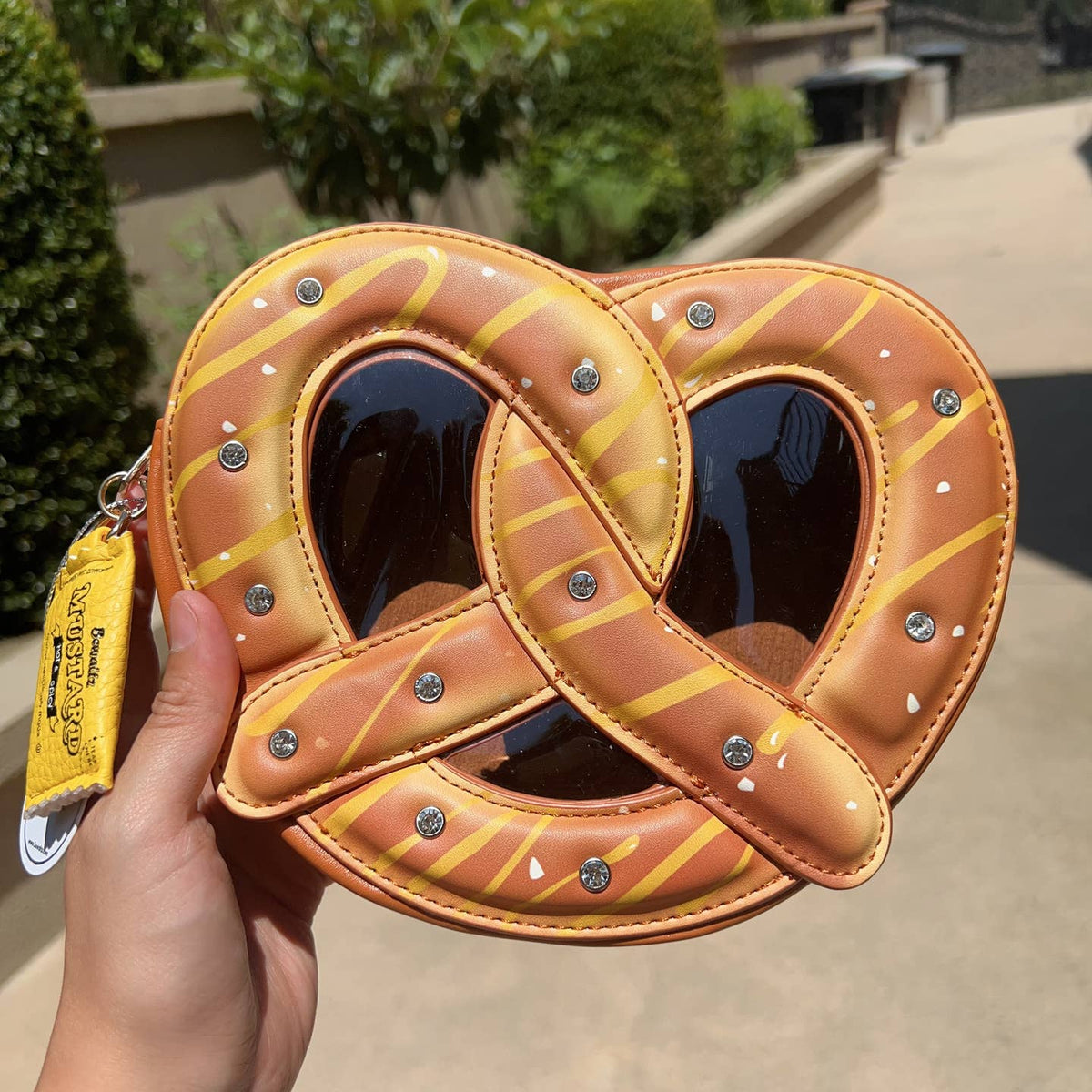 Heart-shaped pretzel purse held by a hand outdoors