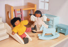 Two wooden doll figures playing in a miniature room setting with a wooden bunk bed, a slide, a light blue rocking horse, a chest of drawers, and a bedside table.