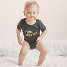 Child wearing a 'Little Brother' onesie on a white background
