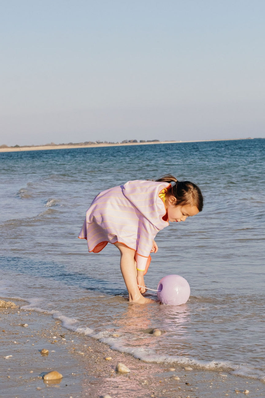 Child playing with a ball in shallow water at the beach