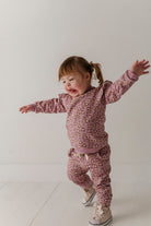 Child wearing a pink leopard print outfit on a white background