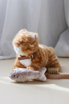 Plush cat toy with grooming tools on a light surface